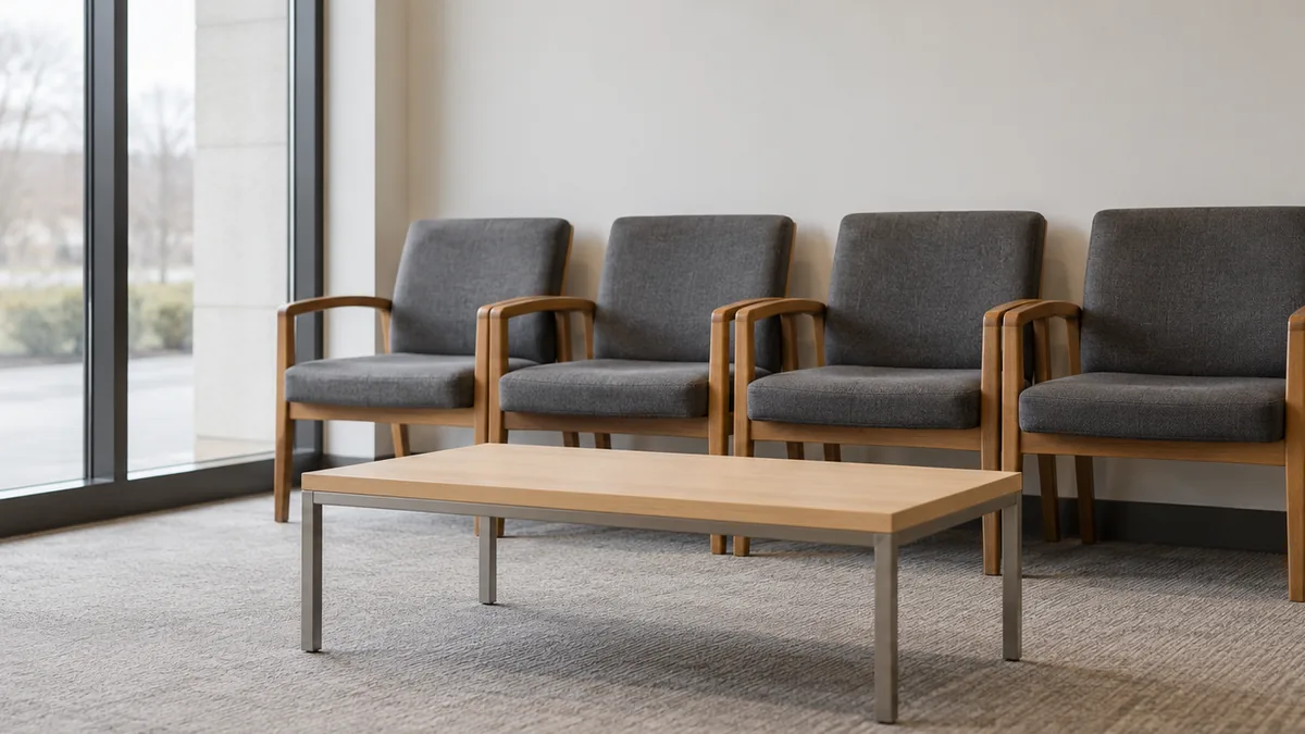 A row of empty chairs and a low table in a bright waiting area