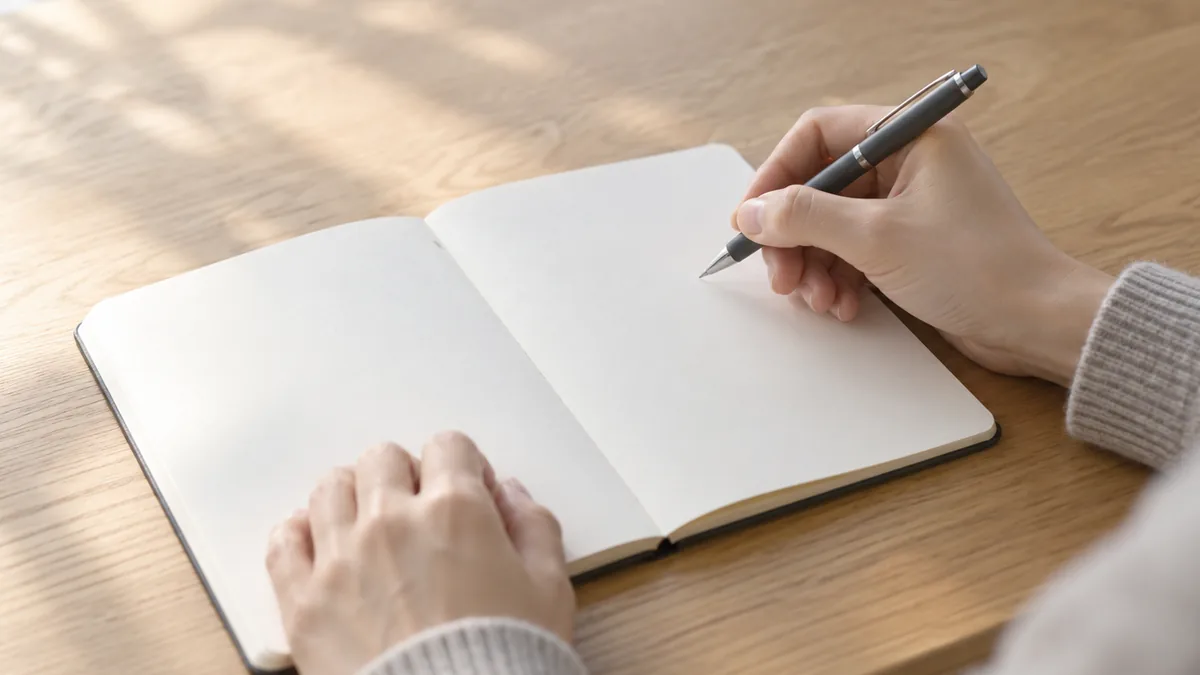 白紙のノートの上でペンを持ち、書く準備をする両手